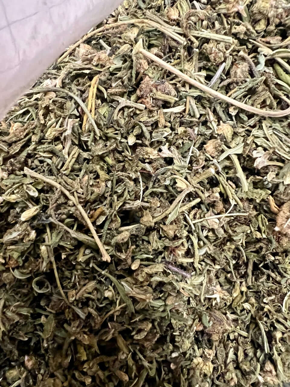 Close-up of Ripkitty Delta 8 Glue Flower CBD trim showcasing green plant matter and natural texture.