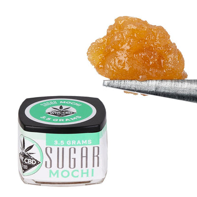 WNC CBD THCA Sugar in a 3.5 grams jar with a golden crystalline texture being held by a tool.