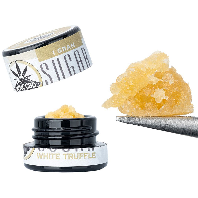 WNC CBD THCA Sugar in a jar with a scoop showing its rich yellow texture and flavor.
